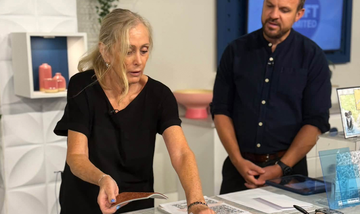 Karen demonstrating at the studio craft table with the presenter watching